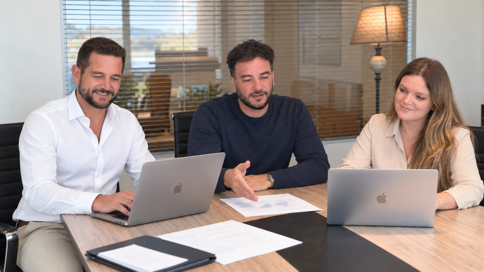 Equipo de Achia Group reunido alrededor de una mesa con documentos comerciales y computadoras.
